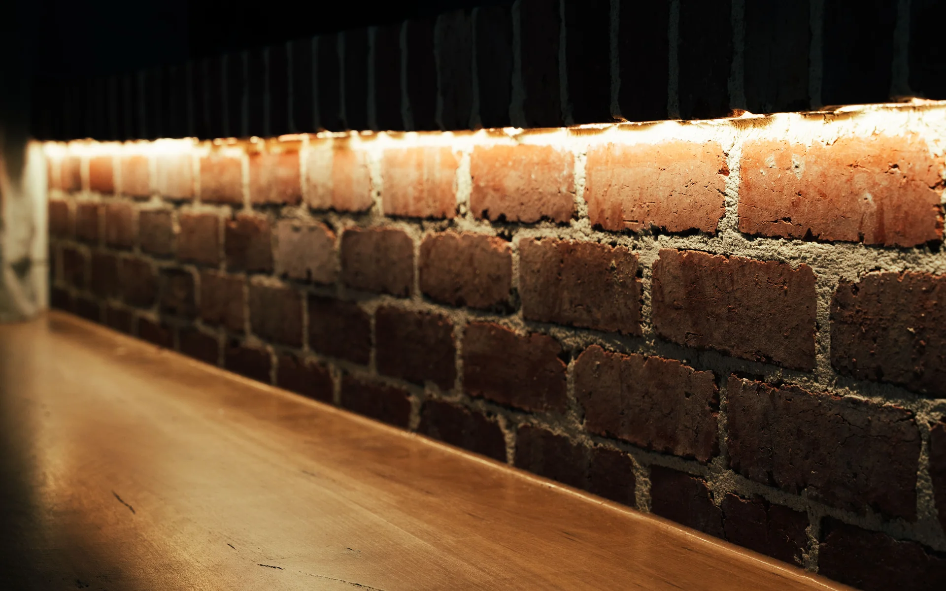 Warm LED strip lighting running along an exposed brick wall