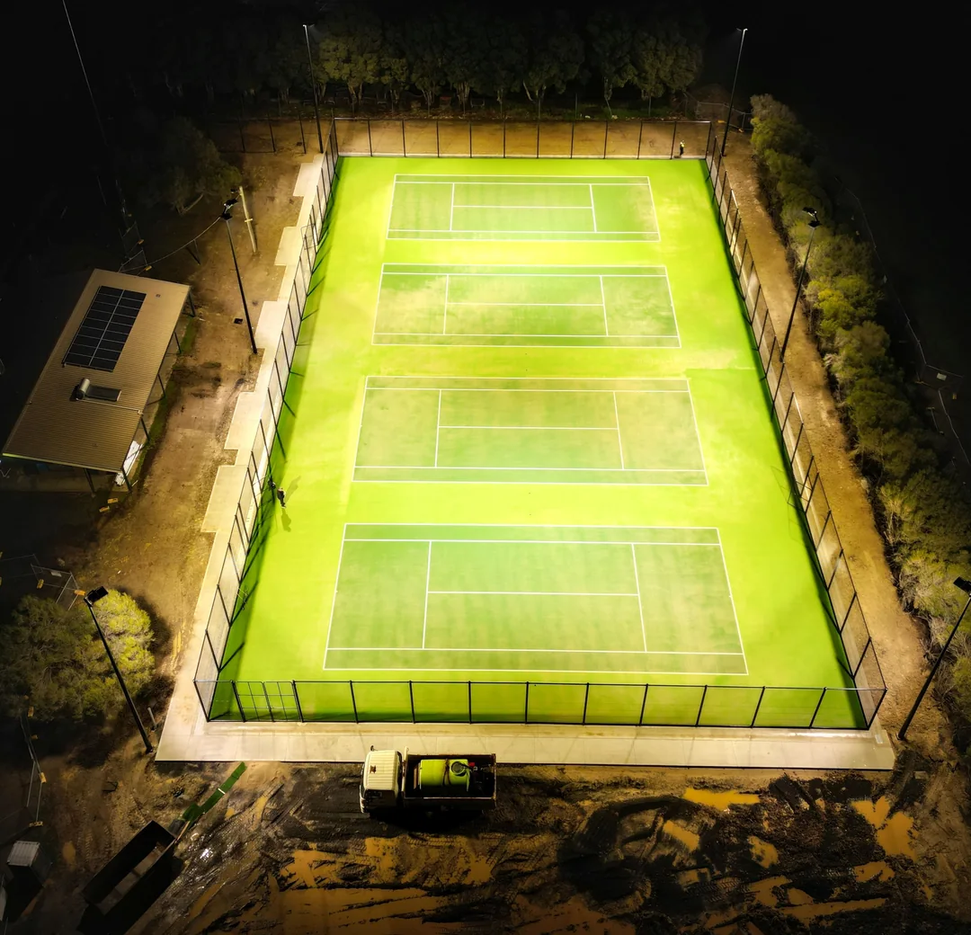 Aerial view of an outdoor tennis court lit at night